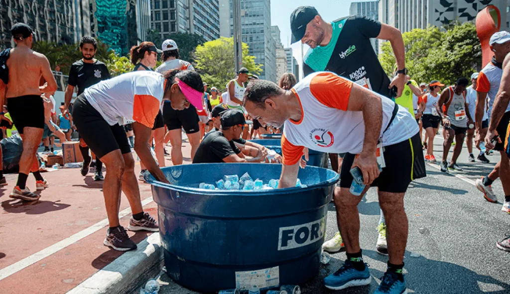 atletas da são silvestre 22 pegando água mineral para consumir e realizar o descarte correto e os copos serem destinados à reciclagem