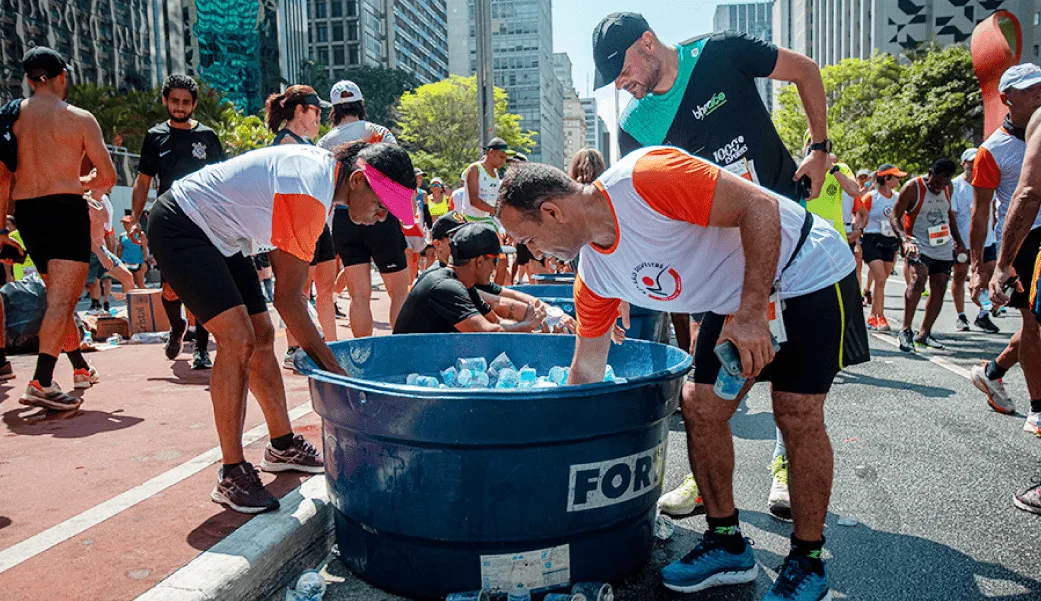 atletas da são silvestre 22 pegando água mineral para consumir e realizar o descarte correto e os copos serem destinados à reciclagem