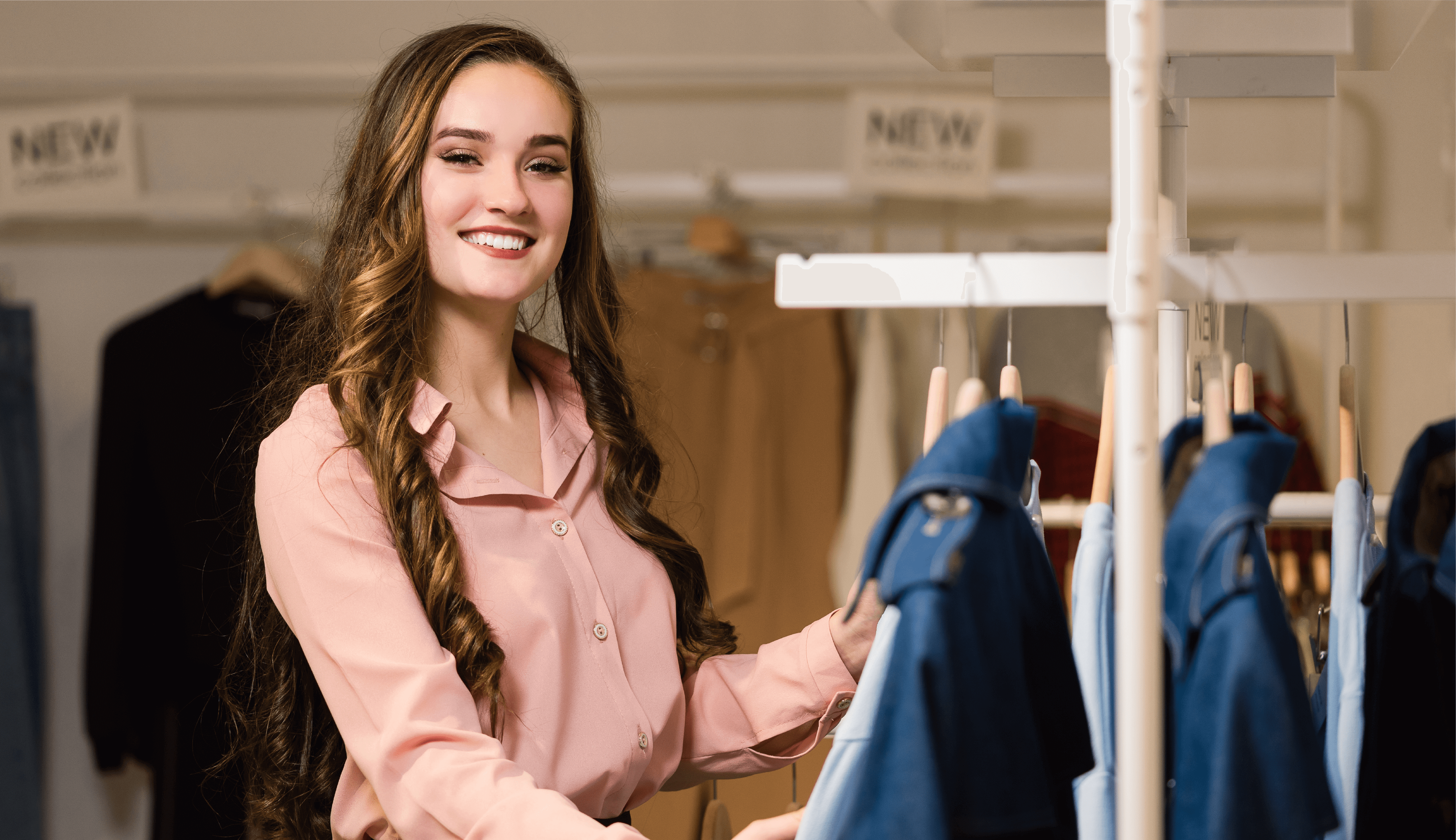 Mulher sorridente explorando opções de vestuário em uma loja de moda slow fashion para uma moda mais sustentável.