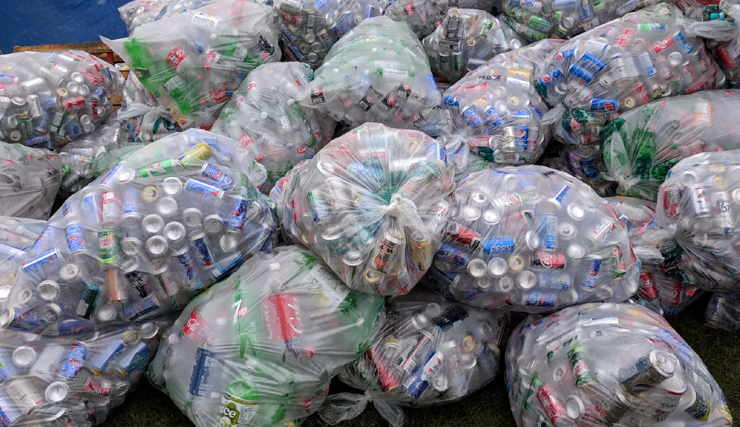 Sacos transparentes cheios de garrafas plásticas prontas para a reciclagem, destacando o volume de resíduos e a importância da reciclabilidade.