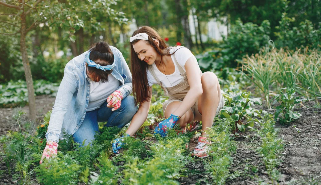 Duas mulheres cultivando plantas e promovendo práticas de agricultura sustentável.